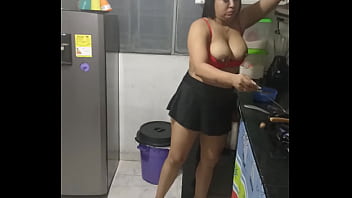 Nackte Hausfrau kocht verführerisch Würstchen in der Küche